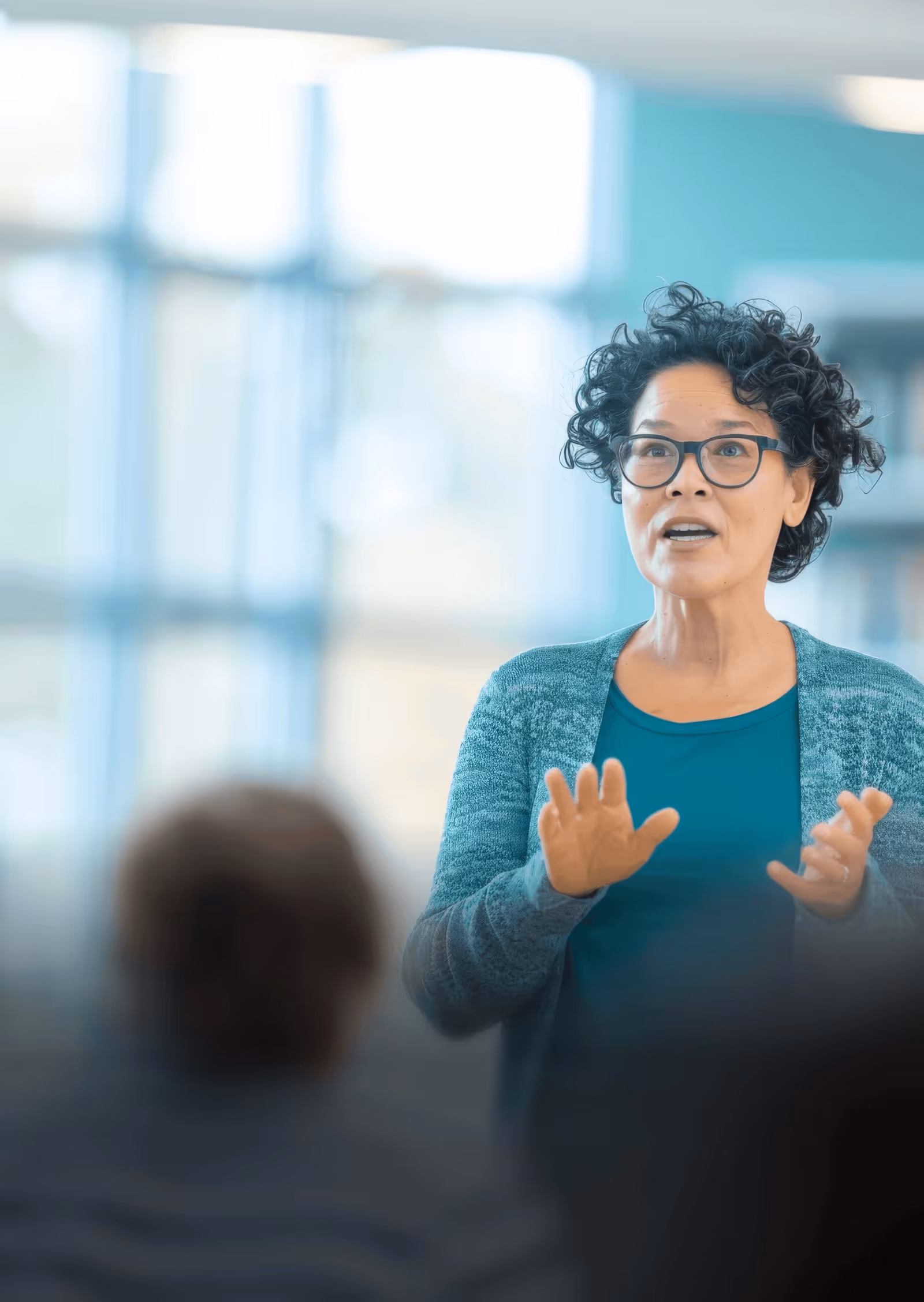 photo of a woman talking or presenting to some people